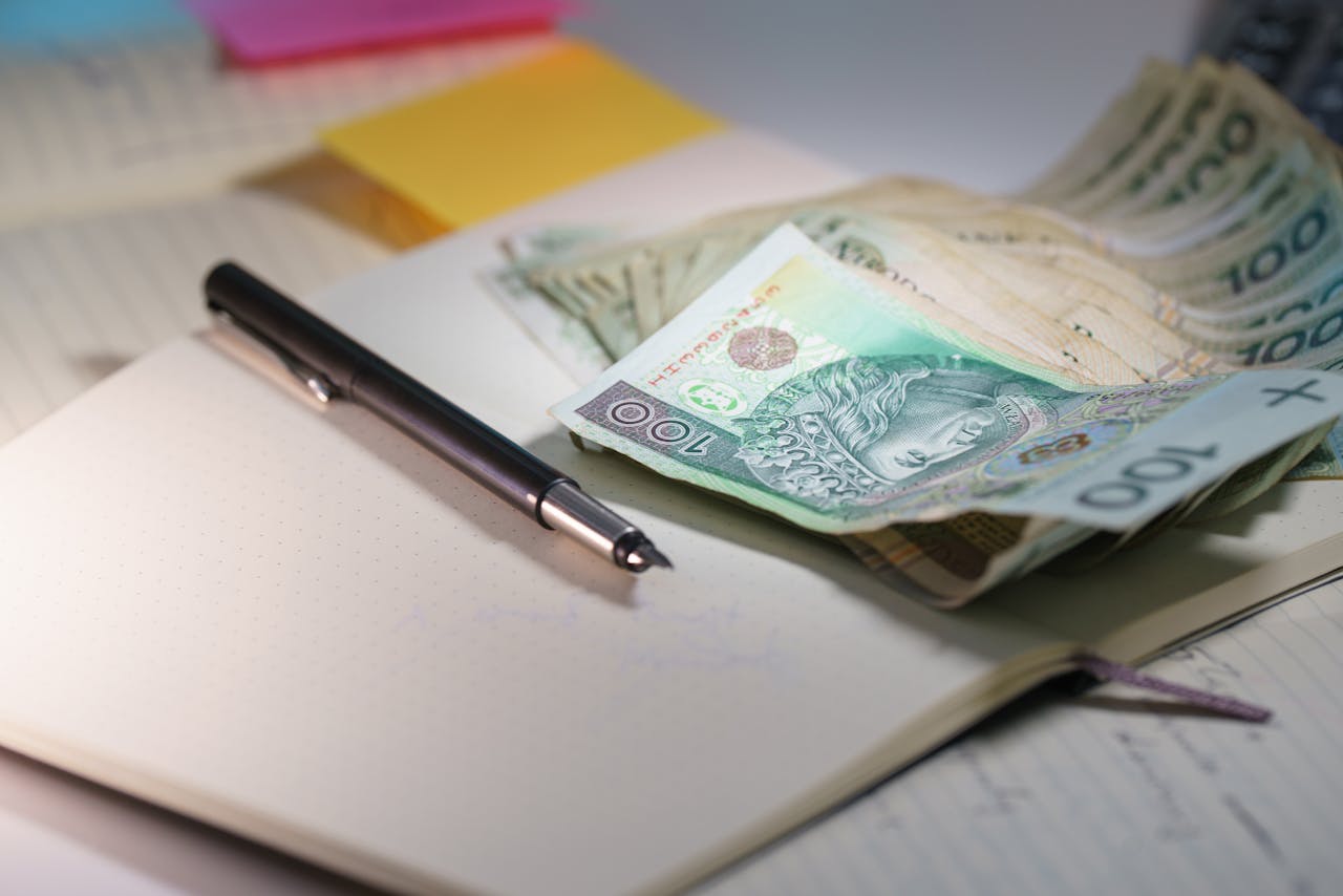 Close-up of Polish Zloty banknotes on an open notebook with a pen, symbolizing finance and budgeting.